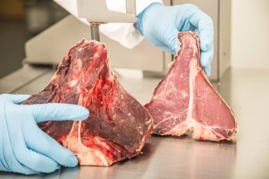 Şerit testere tezgahı üzerinde çalışan bir et dükkanda eti kesip. Dilimleme ve kesme T-Bone biftek pazarında.