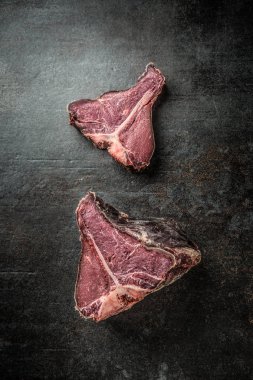 Yakın çekim ham T-bone biftek siyah kesme tahtası üzerinde.