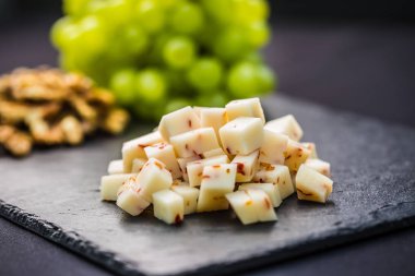 Peynir sulu üzüm ve kayrak tahta üzerinde ceviz parçaları.