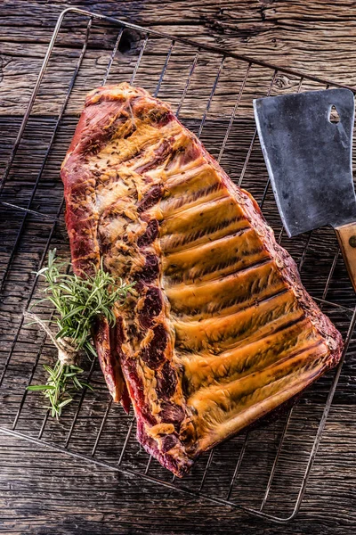 Smoked raw pork ribs and rosemary herbs on wooden board.