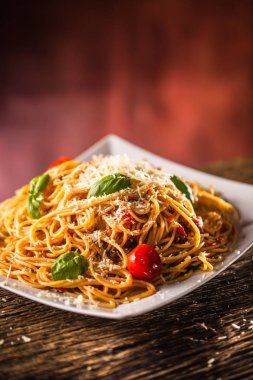 İtalyan makarna spagetti beyaz tabakta domates sosu fesleğen ve parmesan peyniri ile.