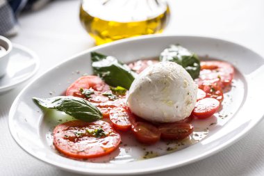 Mozzarella peyniri domates fesleğen zeytinyağı bir baharat üzerinden Caprese salatası.
