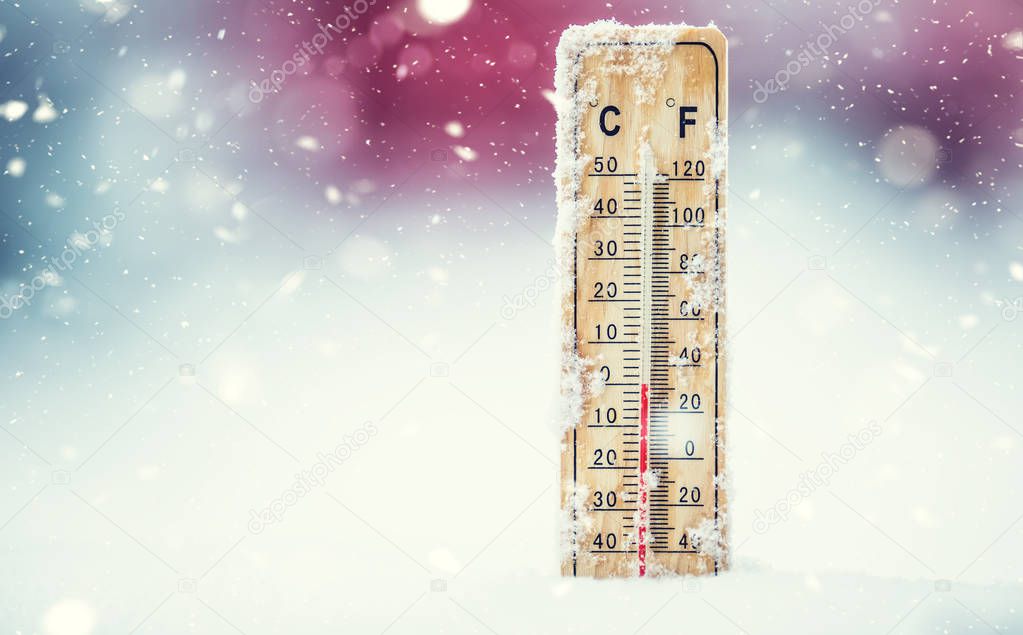 Thermometer on snow shows low temperatures in celsius or farenheit.