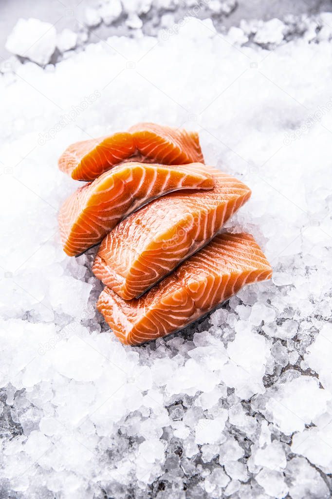 Salmon fillets portioned on ice and empty kitchen board.