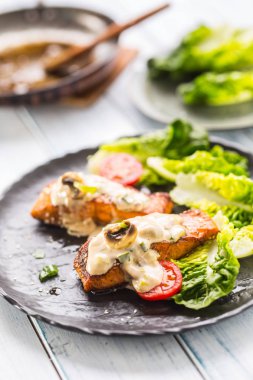 Lezzetli kızarmış somon fileto veya biftek mantar sosu susam domates ve marul salatası ile ızgara.