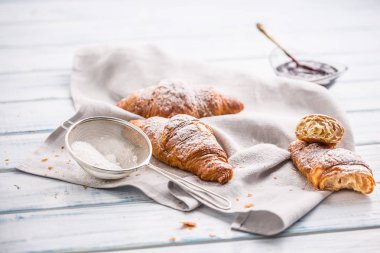 Mutfak masasının üzerine pudra şekeri serpilir taze tereyağı kruvasan.