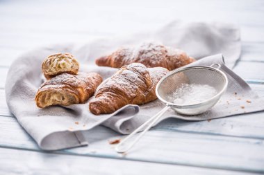 Mutfak masasının üzerine pudra şekeri serpilir taze tereyağı kruvasan.
