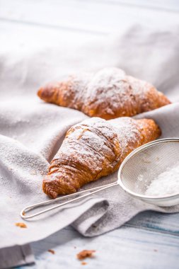 Mutfak masasının üzerine pudra şekeri serpilir taze tereyağı kruvasan.