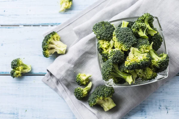 Fresh broccoli in bowl on kitchen table.