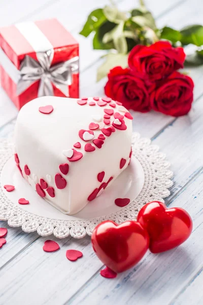 赤いハートのハートの形をしたマジパンの白いケーキ リボンからの贈り物は赤いバラの装飾花束 結婚式やバレンタインの日の概念 — ストック写真