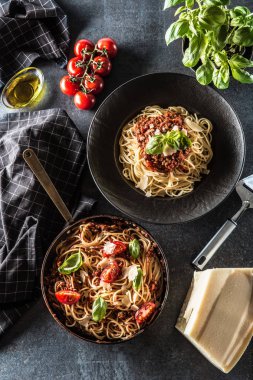 Üst görünüm İtalyan makarna spagetti bolognese plaka ve domates ve fesleğen ile pan