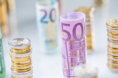 Diğer konumda haddelenmiş euro banknot ve madeni paraların kuleleri yığılmış