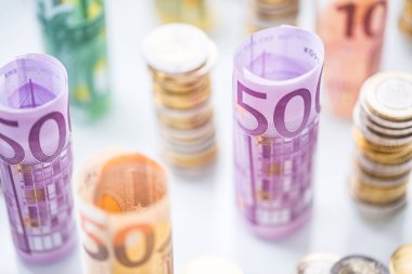 Diğer konumda haddelenmiş euro banknot ve madeni paraların kuleleri yığılmış