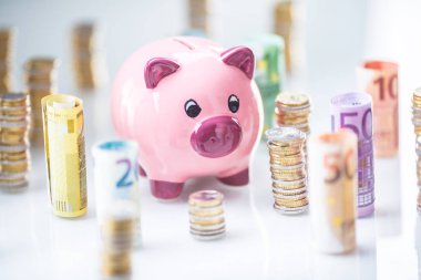 Pembe kumbara ortasında haddelenmiş euro banknot ve kule