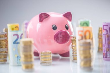 Pembe kumbara ortasında haddelenmiş euro banknot ve kule