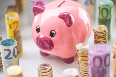 Pembe kumbara ortasında haddelenmiş euro banknot ve kule