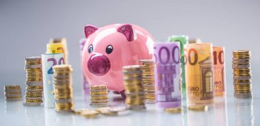 Pembe kumbara ortasında haddelenmiş euro banknot ve kule