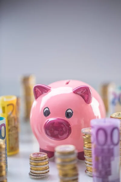 Hucha rosa en medio de billetes en euros laminados y torre — Foto de Stock