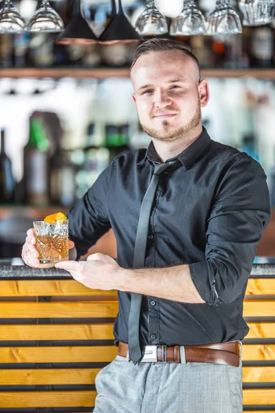 Бармен стоит перед баром и в руке держа кокта — стоковое фото