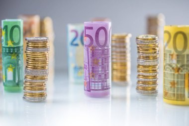 Diğer pozisyonlarda haddelenmiş euro banknot ve madeni paraların kuleleri yığılmış