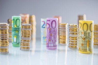 Diğer pozisyonlarda haddelenmiş euro banknot ve madeni paraların kuleleri yığılmış