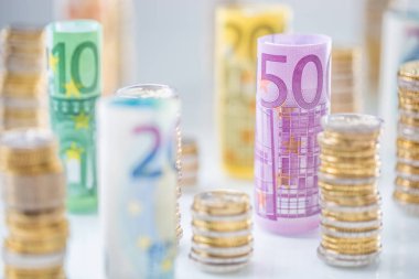 Diğer pozisyonlarda haddelenmiş euro banknot ve madeni paraların kuleleri yığılmış