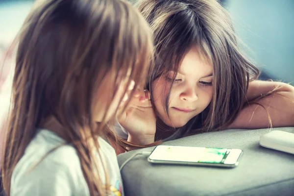 Симпатичные маленькие сестры-близнецы с помощью современного смартфона . — стоковое фото
