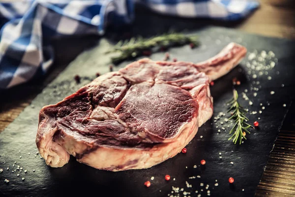 Filete de res de tomahawk crudo con sal, pimienta y romero en plato de pizarra — Foto de Stock