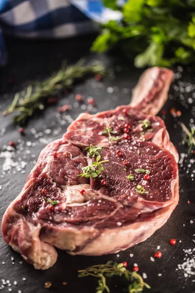 Filete de res de tomahawk crudo con sal, pimienta y romero en plato de pizarra — Foto de Stock