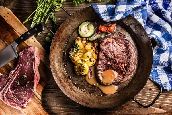 Saftig nötkött Rib Eye steak rostad potatis med sås grillad grönsaker salt peppar och örter i vintage pan — Stockfoto