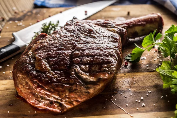 Bistecca di tomahawk appena grigliata su piatto di ardesia con sale pepe rosmarino ed erbe di prezzemolo — Foto Stock