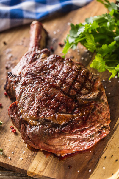 Свежеприготовленный стейк томагавк на тарелке с соленым перцем розмарин и травы петрушки
