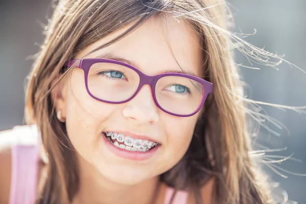Portret van gelukkig lachend meisje met tandheelkundige accolades en glazen — Stockfoto