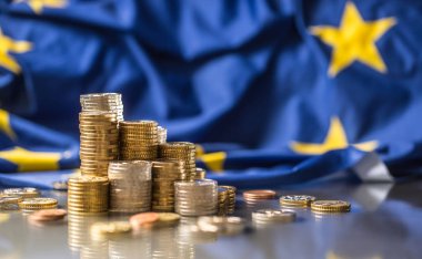 Arka planda euro sikke ve Avrupa Birliği bayrağı olan kuleler
