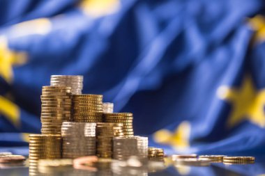 Arka planda euro sikke ve Avrupa Birliği bayrağı olan kuleler