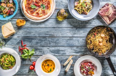 Tabak ve tava üzerinde İtalyan yemekleri tam tablo görünümünde top. Pizza makarna risotto çorbası ve balık sebze salatası
