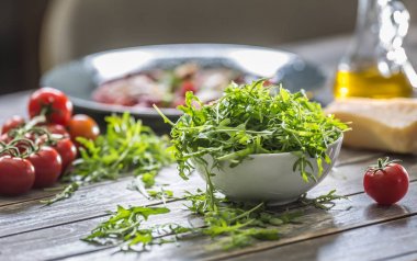 Ahşap masada beyaz çanak taze arugula salatası