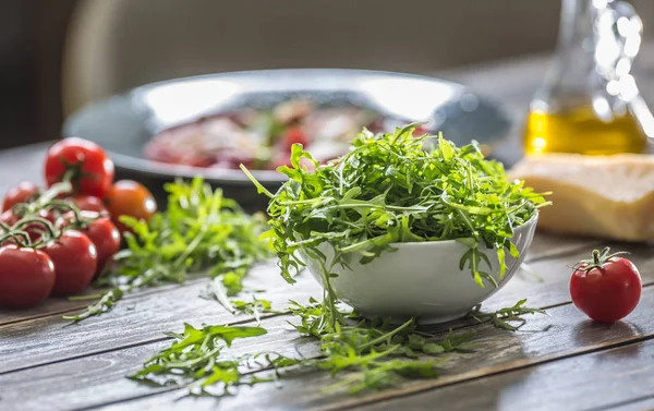 Salată proaspătă de arugula în farfurie albă pe masă de lemn — Fotografie, imagine de stoc