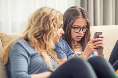 Oturma odasında akıllı telefonlar kullanarak iki genç girs veya kız kardeş