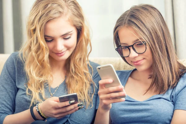 Oturma odasında akıllı telefonlar kullanarak iki genç girs veya kız kardeş — Stok fotoğraf