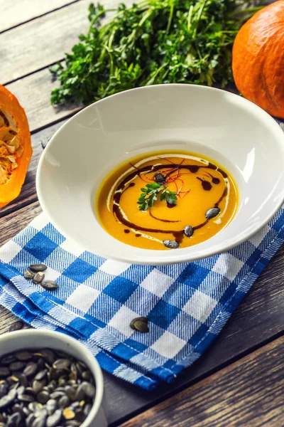 Pumpkin cream soup with seeds and parsley on kitchen table — Stock Photo, Image