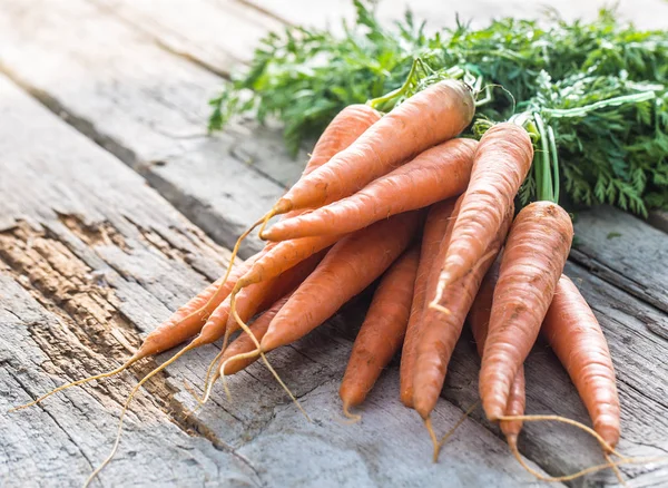 Букет свіжої моркви вільно лежить на старій садовій дошці — стокове фото