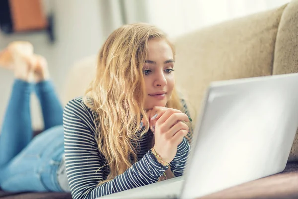 Menina bonita usando computador portátil na sala de estar — Fotografia de Stock