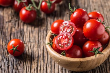 Fresh cherry tomatoes in wooden bowl on old oak table