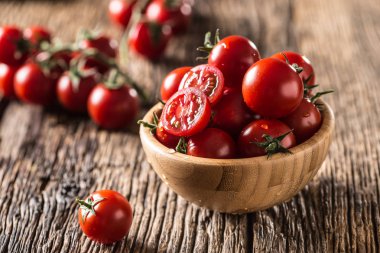 Fresh cherry tomatoes in wooden bowl on old oak table