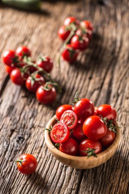 Fresh cherry tomatoes in wooden bowl on old oak table