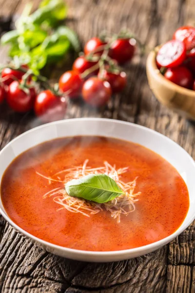 Sopa de tomate caliente queso parmesano y albahaca dejan en la vieja mesa de roble — Foto de Stock