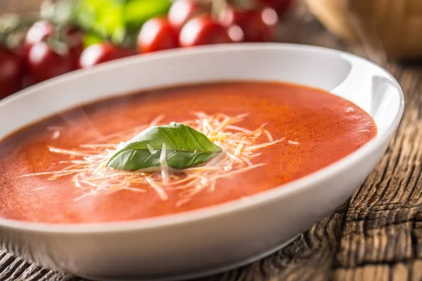 Hot tomato soup parmesan cheese and basil leave on old oal table — Stock Photo, Image