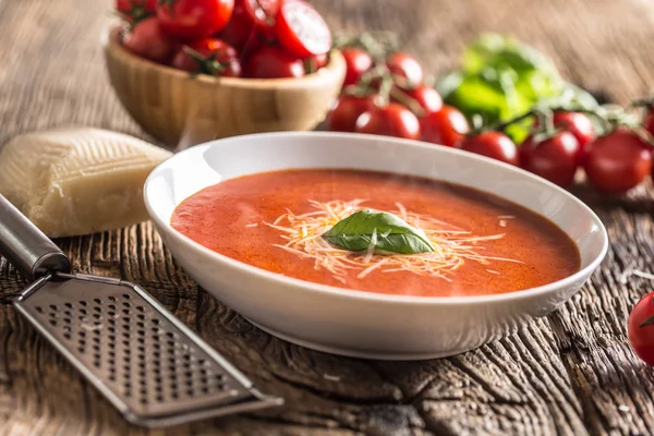 Sopa de tomate caliente queso parmesano y albahaca dejan en la vieja mesa de roble — Foto de Stock