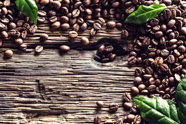 Top nézet kávébab és zöld levelek rusztikus tölgyfa asztal — Stock Fotó